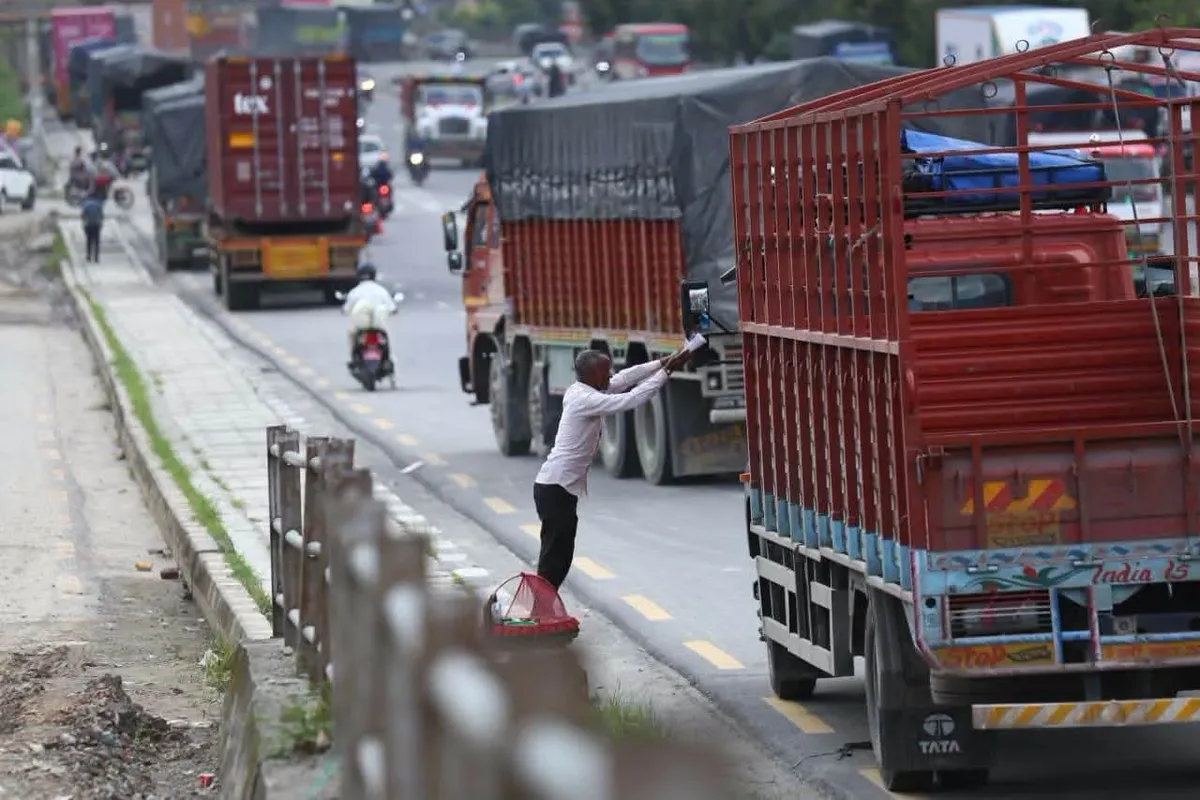 A street vendor stands between lines of stalled freight trucks on the Kathmandu ring road after the Prithvi Highway was cut