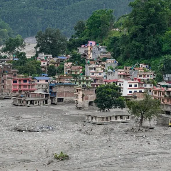 A dense hillside town above a vast new plain of grey silt where the lowest buildings stood
