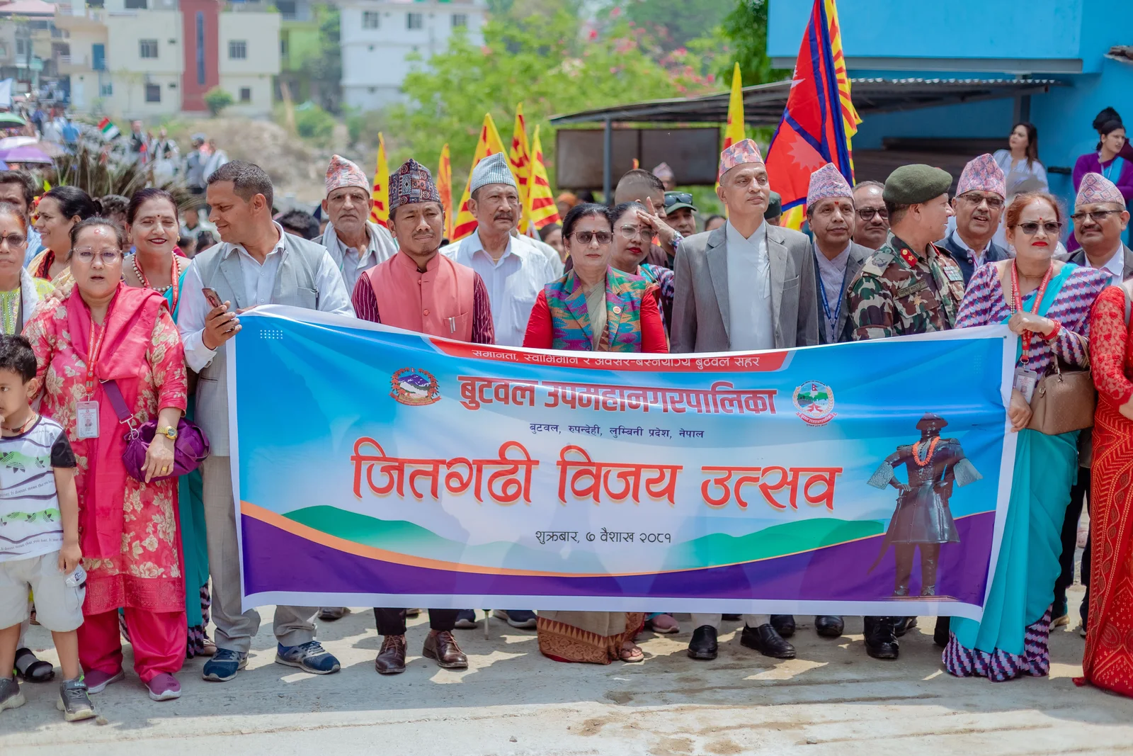 A lively crowd celebrating the Jitgarhi Victory Festival in Butwal, Nepal with traditional attire and colorful flags.