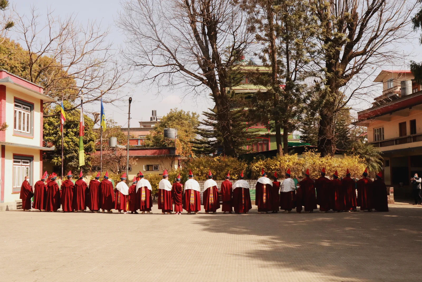 A group of monks in red robes gathering outside a Buddhist monastery in Kathmandu, Nepal.