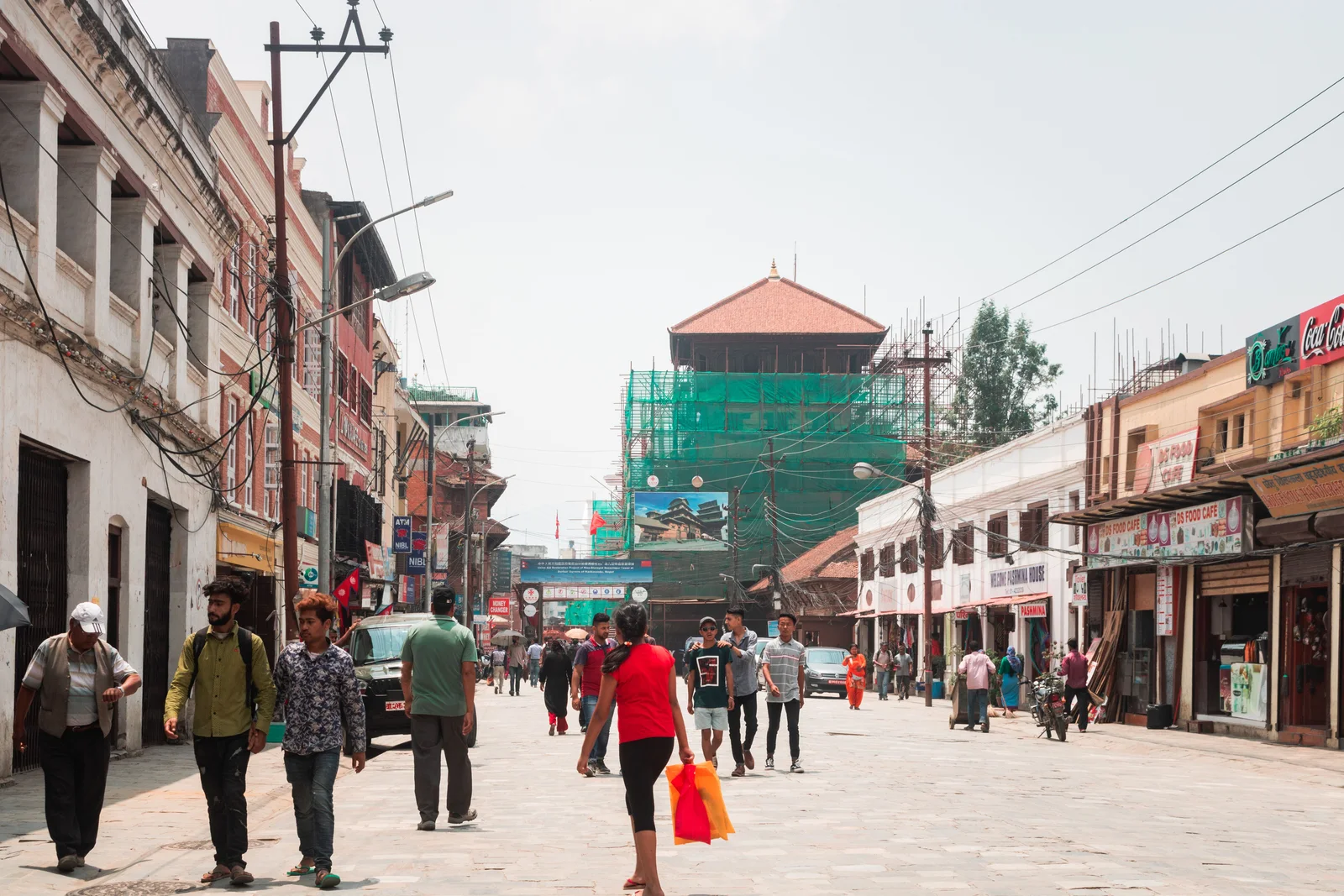 Vibrant street life in Kathmandu with locals and shops on a sunny day.